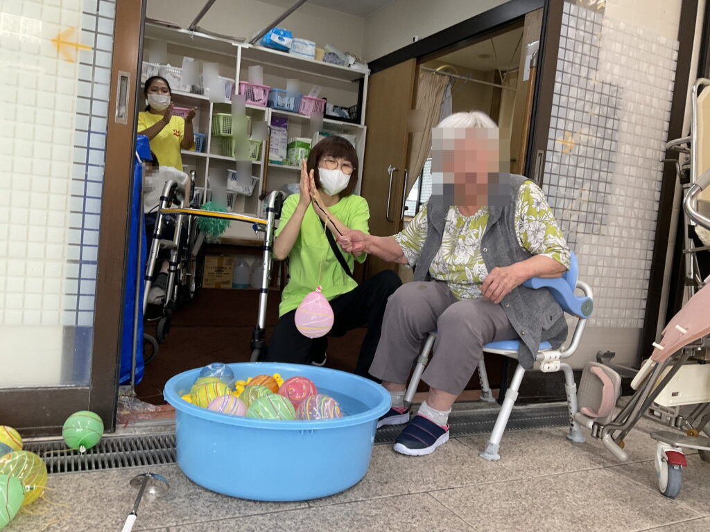 色とりどりのヨーヨーが浮かぶたらいから、こよりでヨーヨーを釣り上げるご利用者様